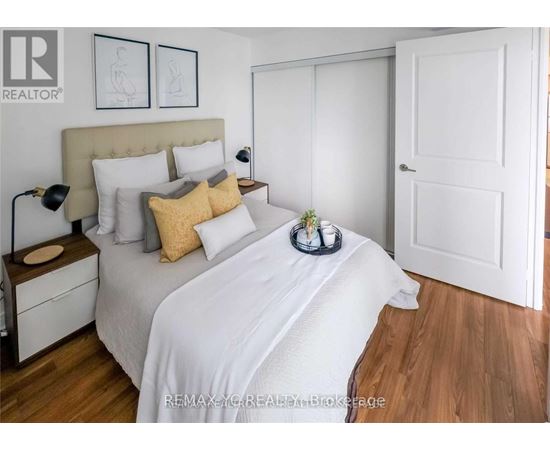 A bedroom with a white bed and a wooden floor.