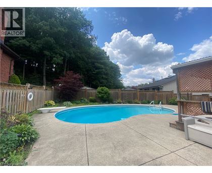 A pool surrounded by a wooden fence and greenery.