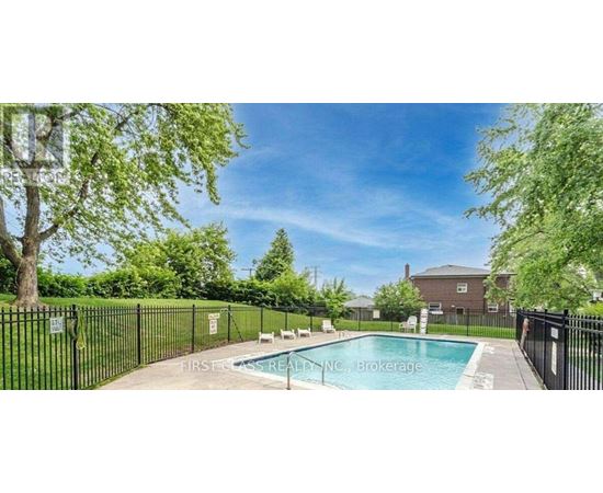 A pool surrounded by a black fence with trees in the background.