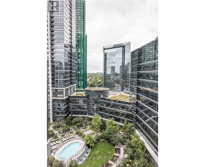A modern building complex with a pool and greenery.