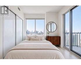 A bedroom with a large bed and a view of the city.