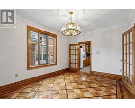 A large, empty room with wooden floors and a chandelier.