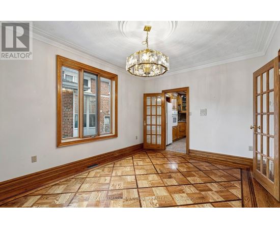 A large, empty room with wooden floors and a chandelier.