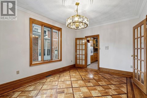 A large, empty room with wooden floors and a chandelier.