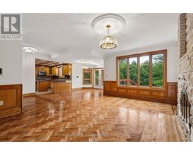 A large open living room with wood flooring and a chandelier.