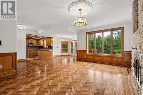 A large open living room with wood flooring and a chandelier.