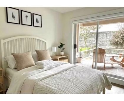A bedroom with a large bed and a view of a garden outside.