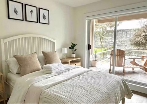 A bedroom with a large bed and a view of a garden outside.