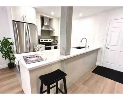 A kitchen with a white countertop and a black stool.