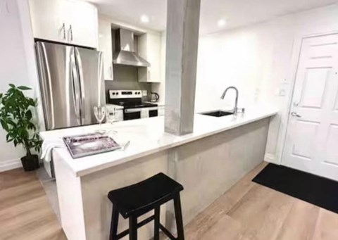 A kitchen with a white countertop and a black stool.