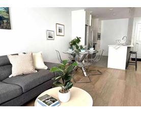 A living room with a grey couch, a coffee table, and a dining table set up.