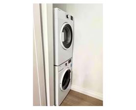 A white front loading washing machine in a room.