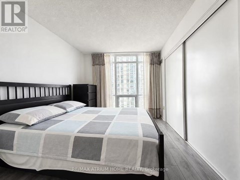 A bedroom with a large bed and a window with curtains.