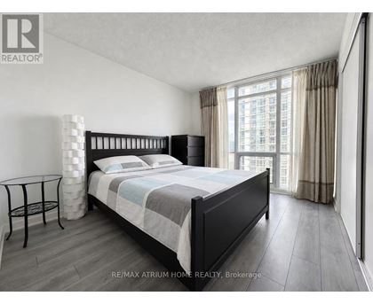 A bedroom with a large bed and a view of a building outside the window.