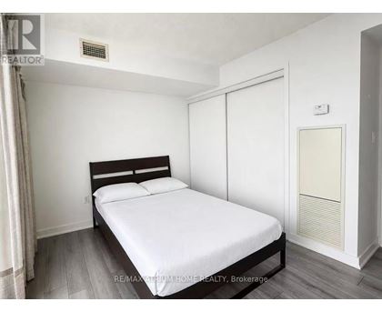 A bedroom with a bed, wooden headboard, and a white mattress.