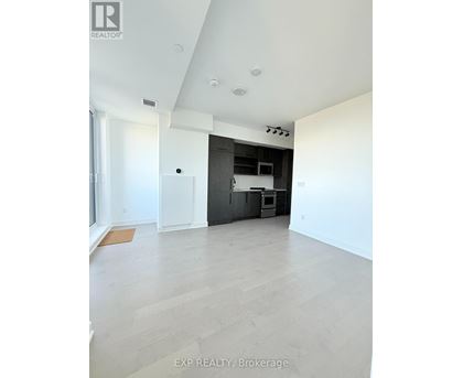 A spacious room with a kitchen area in the background.