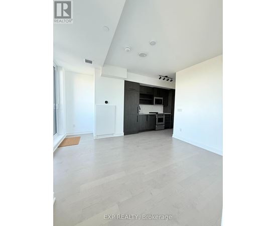 A spacious room with a kitchen area in the background.