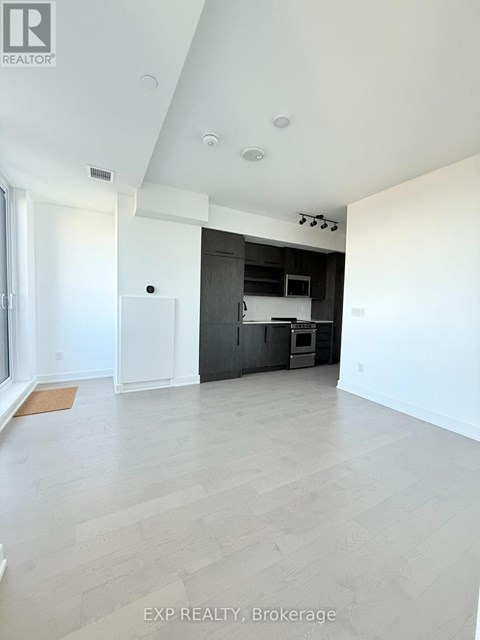 A spacious room with a kitchen area in the background.