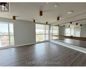 A spacious room with wooden flooring and large windows.