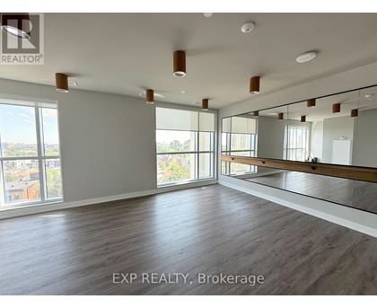 A spacious room with wooden flooring and large windows.