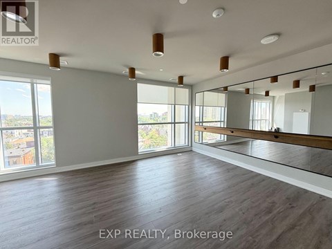 A spacious room with wooden flooring and large windows.
