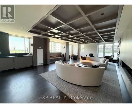 A spacious living room with a curved sofa and a large window.