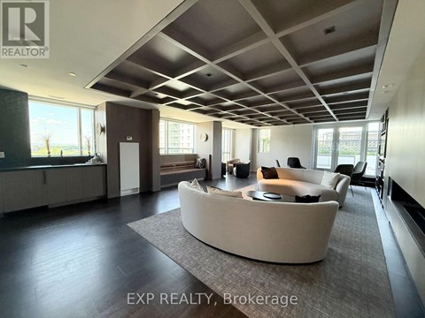 A spacious living room with a curved sofa and a large window.