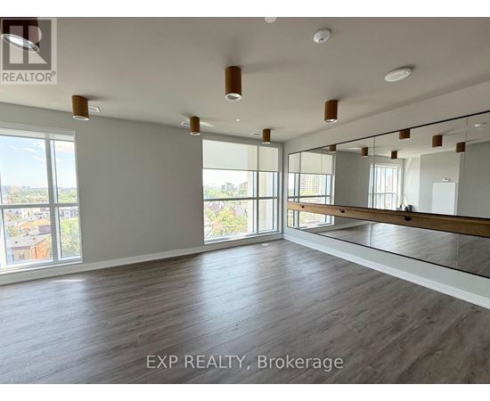 A spacious room with wooden flooring and large windows.