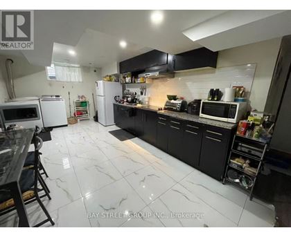 A kitchen with black cabinets and white marble flooring.