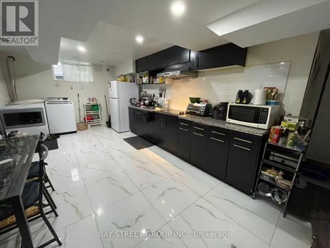 A kitchen with black cabinets and white marble flooring.