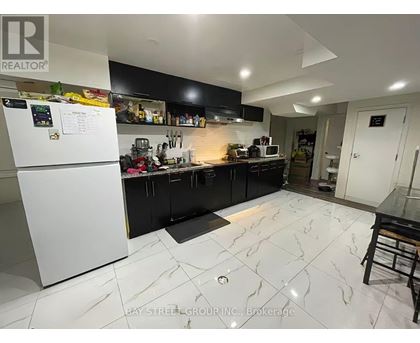 A kitchen with a white fridge and black cabinets.