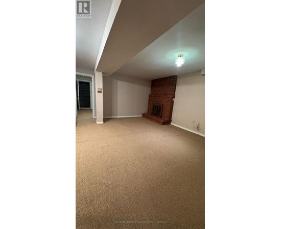 A room with a carpeted floor and a brick fireplace.