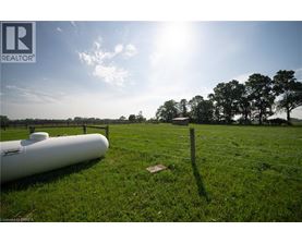 A field with a fence and a white pipe on the ground.