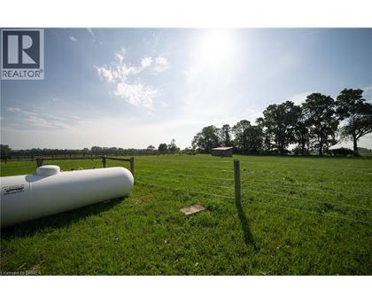 A field with a fence and a white pipe on the ground.