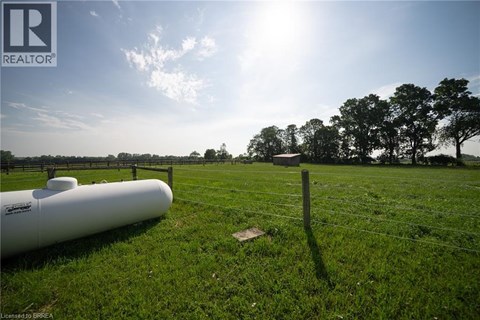 A field with a fence and a white pipe on the ground.