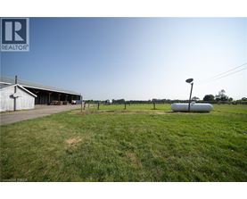 A grassy field with a building and a silo in the background.