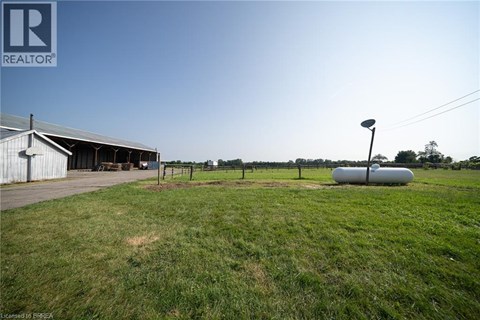 A grassy field with a building and a silo in the background.