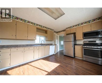 A kitchen with wooden floors and a wallpapered ceiling.