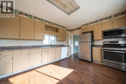 A kitchen with wooden floors and a wallpapered ceiling.