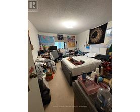 A messy bedroom with a bed, desk, and various items scattered about.