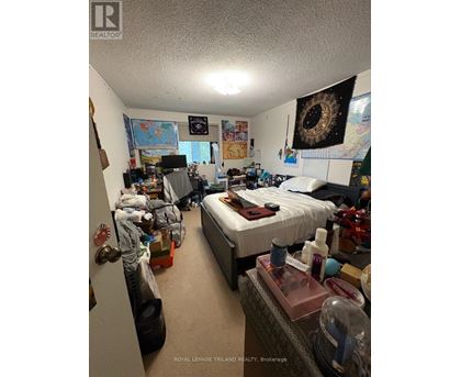 A messy bedroom with a bed, desk, and various items scattered about.