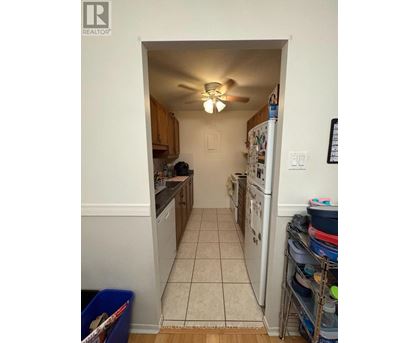 A kitchen with a white fridge and a white ceiling fan.