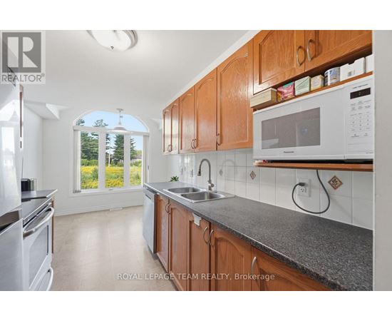 A kitchen with wooden cabinets and a window overlooking a green area.