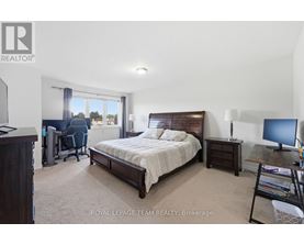 A bedroom with a large bed, a desk with a computer, and a chair with a blue cushion.