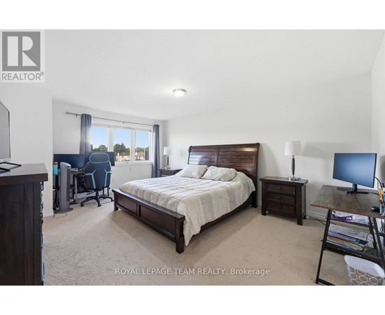 A bedroom with a large bed, a desk with a computer, and a chair with a blue cushion.