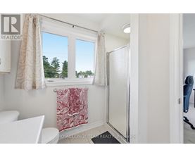A white bathroom with a toilet, sink, and a window with a view of trees.