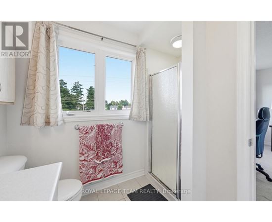 A white bathroom with a toilet, sink, and a window with a view of trees.