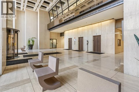 A lobby with a row of chairs and a plant.