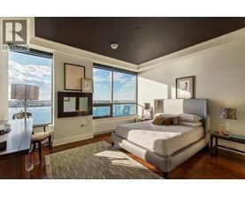 A bedroom with a large bed and a view of the water outside the window.