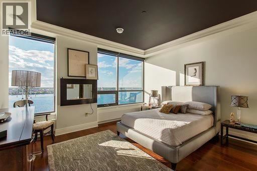 A bedroom with a large bed and a view of the water outside the window.